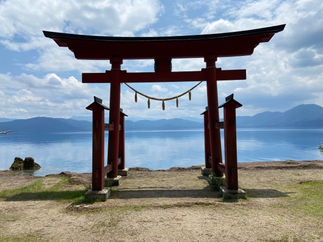 Torii gate of Gozanoishi Shrine overlooking the deep blue waters of Lake Tazawa in Semboku, Akita Prefecture.